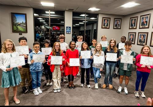 16 Student arbor poster winners holding certificates outside of Madison City Hall where they were recognized