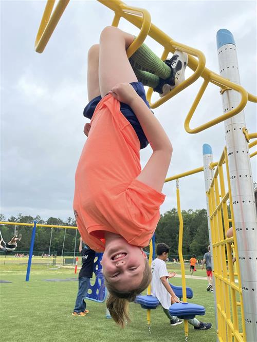 kid hanging upside down on playground bars