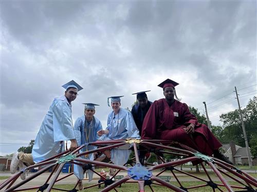 graduates in caps and gowns on playground equipment