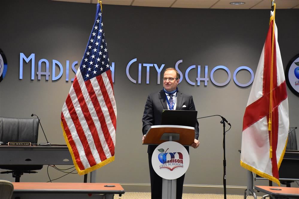  Dr, Nichols at podium flanked by flags
