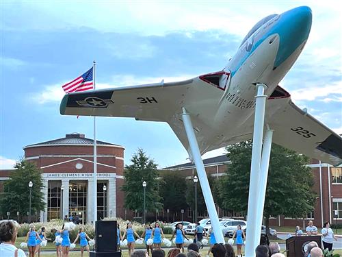 jet on pedestal with school in background