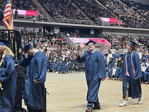 Bob Jones graduate walking toward stage waving  before getting his diploma