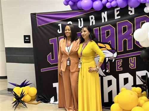principal and teacher at Journey Middle posing before mural