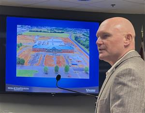  Shane Bagwell at podium with photo of Journey Middle School Construction on large screen behind him