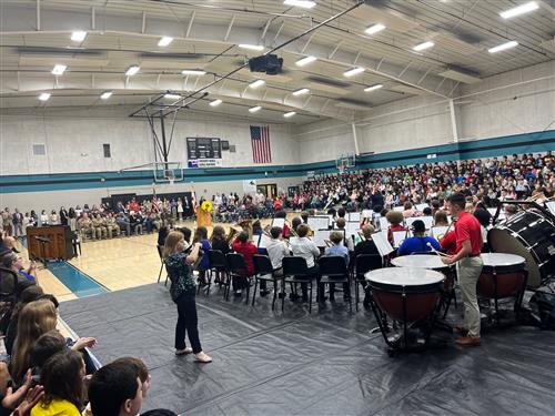 wide angle pic of the Discovery Middle gym filled with veterans, students and the Discovery Middle band