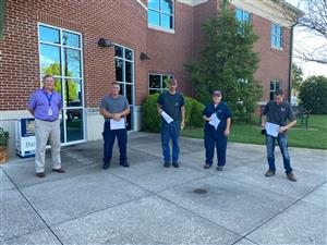 Transportation Director John Wilson with four top mechanics holding their certificates 