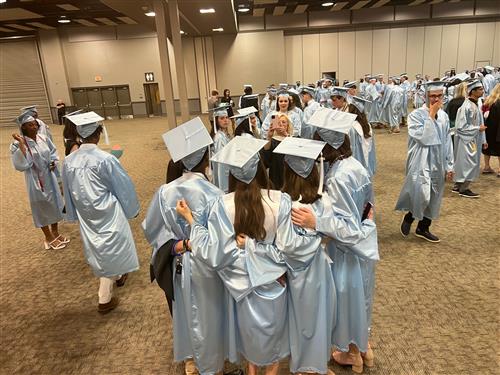 JC friends circle up for pics in their caps and gowns