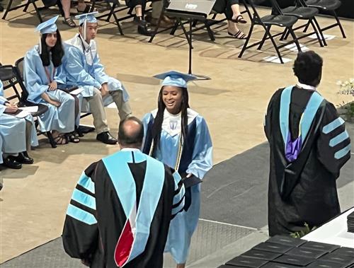 graduate walking across stage receiving diploma