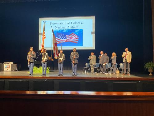 Board members on stage saluting as Color Guard posts flags