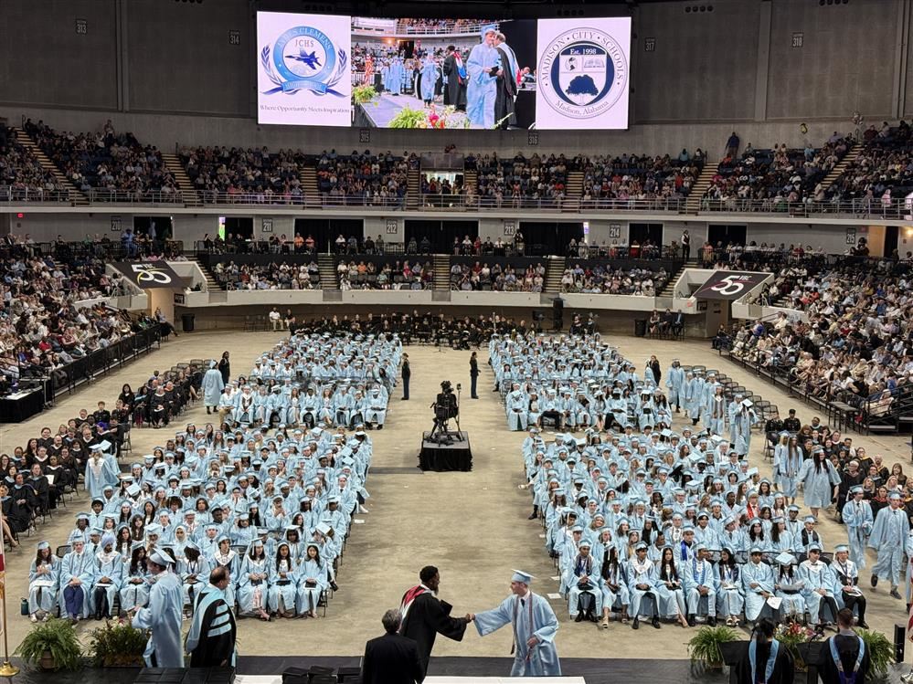  Wide angle view of graduates in caps and gowns seated across civic center arena