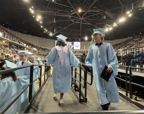 graduates walking off stage with diploma in hand