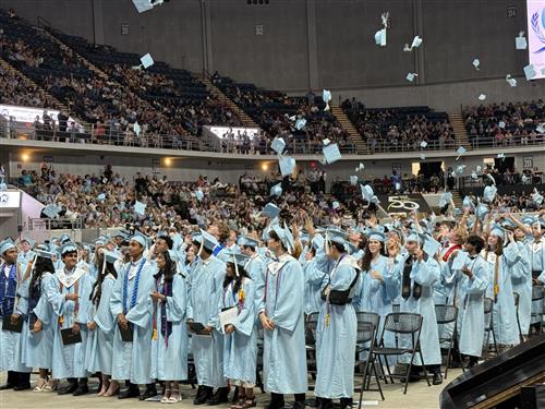 graduates tossing caps from arena floor