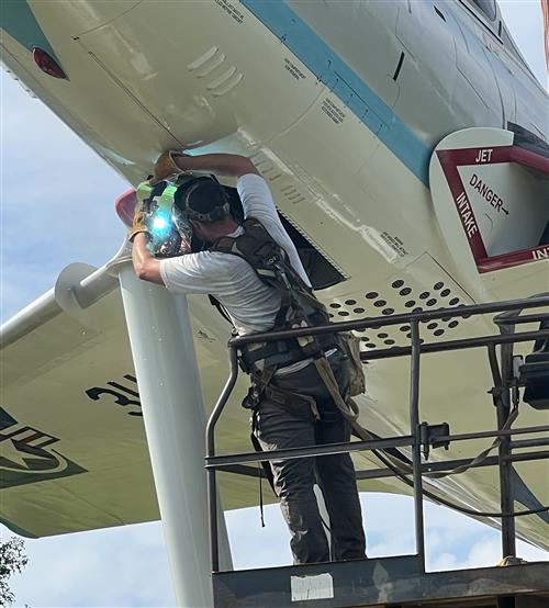 closeup of man welding aircraft underside to mount