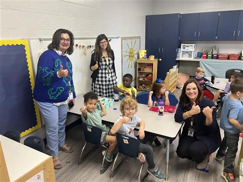 Principal and teachers with kids in a classroom  seated at a table in the new PreK building