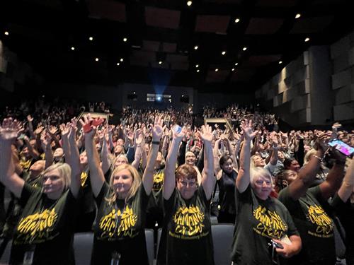 audience in auditorium with arms outstretched