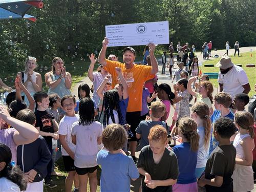 teacher at recess holding up award to cheering students