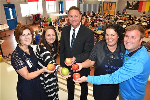 5 officials holding up apples 