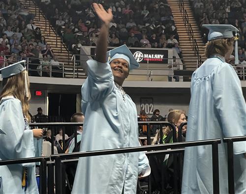 James clemens graduate waving to family in balcony from  ramp to stage