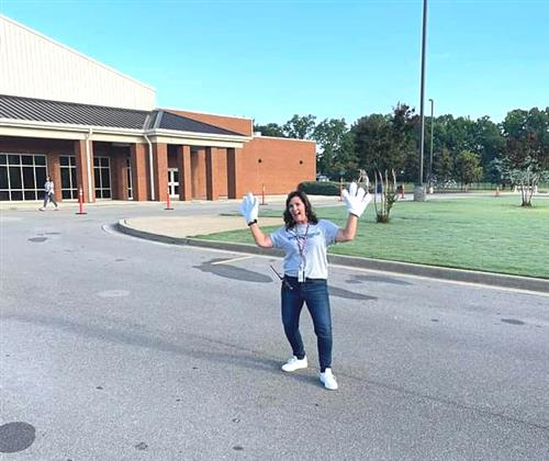 Teacher wearing oversized gloves hamming it up at Mill Creek Elementary