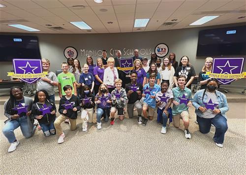 group photo of students in purple holding purple stars representing schools