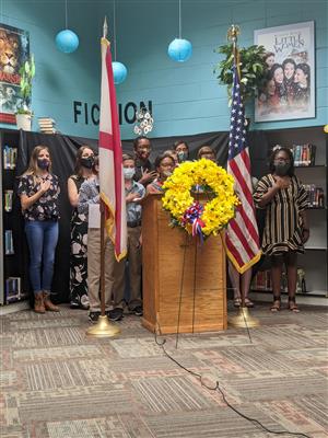 students at podium by flag with hands on heart during pledge 